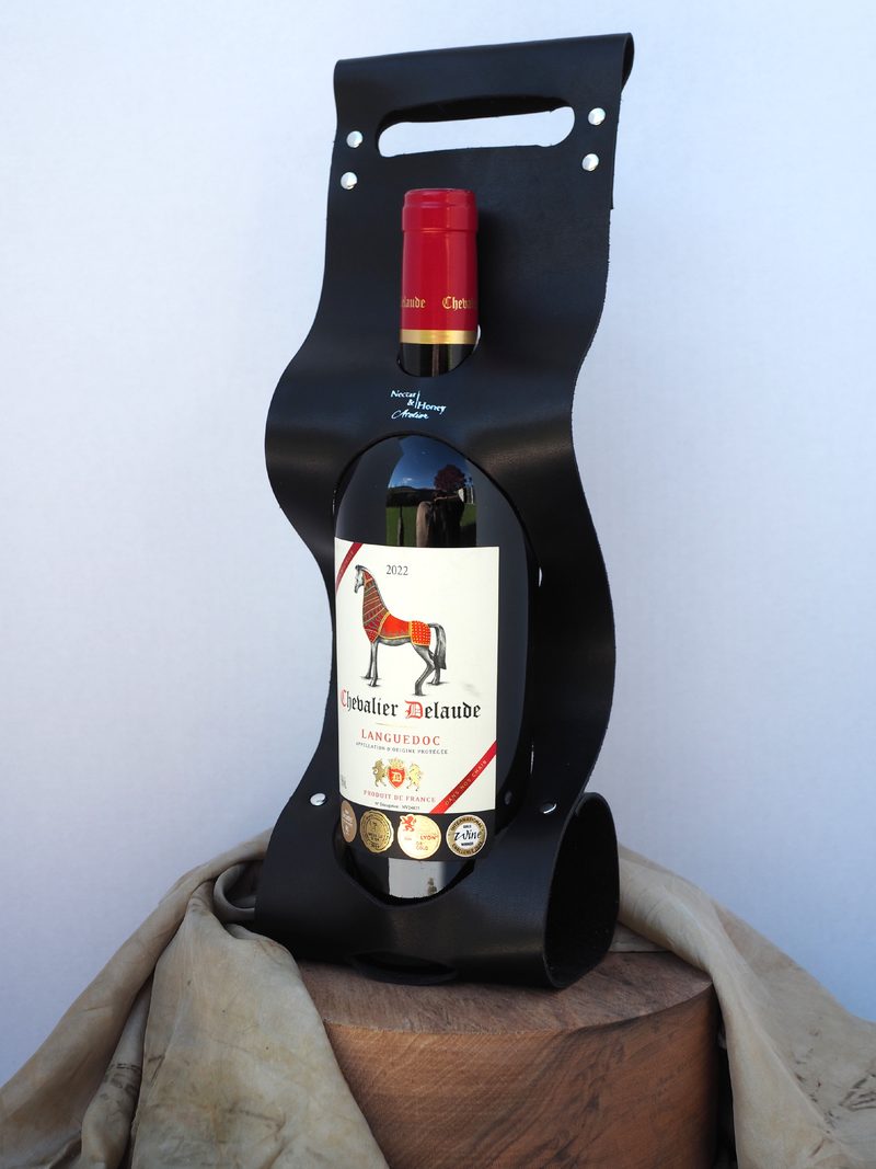 Black leather wine carrier holding a bottle of Chevalier Delaude red